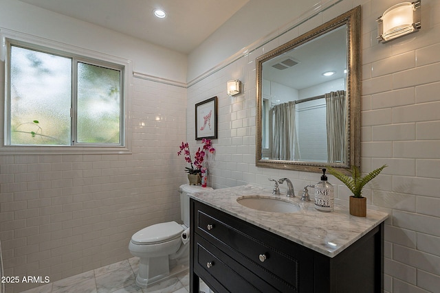 bathroom with vanity, a shower with shower curtain, tile walls, and toilet