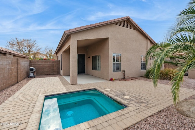 rear view of house featuring a patio area and an in ground hot tub