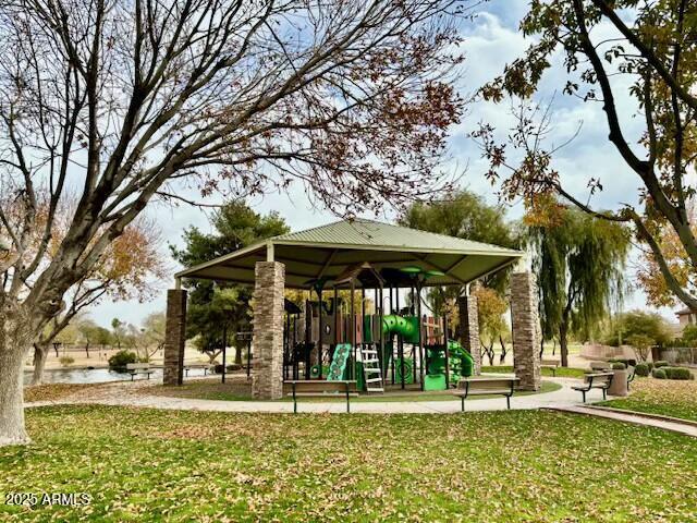 view of community featuring a playground, a yard, and a water view