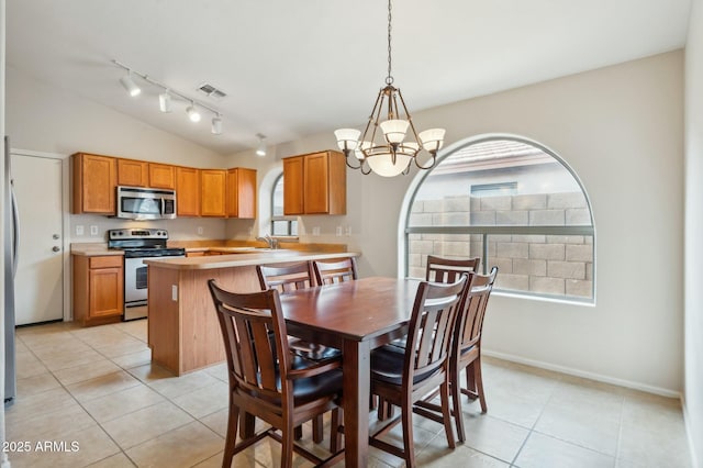 dining space with a notable chandelier, a healthy amount of sunlight, light tile patterned flooring, and lofted ceiling