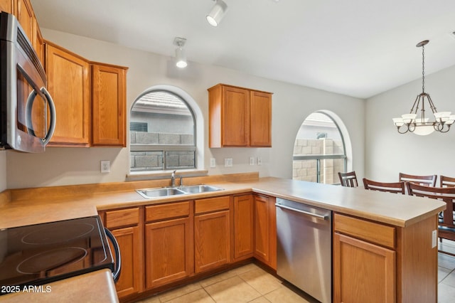 kitchen featuring pendant lighting, sink, appliances with stainless steel finishes, kitchen peninsula, and a chandelier