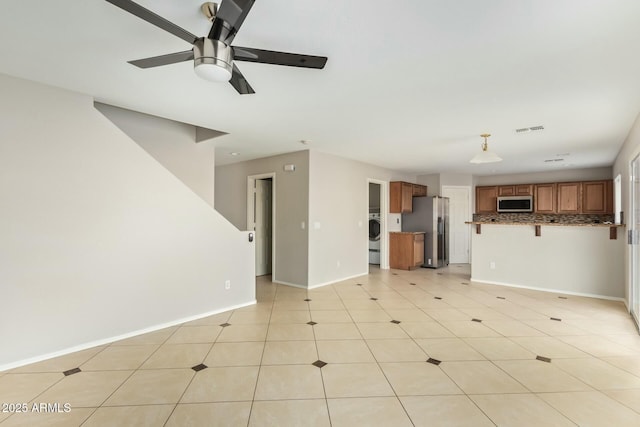 unfurnished living room featuring ceiling fan and washer / clothes dryer