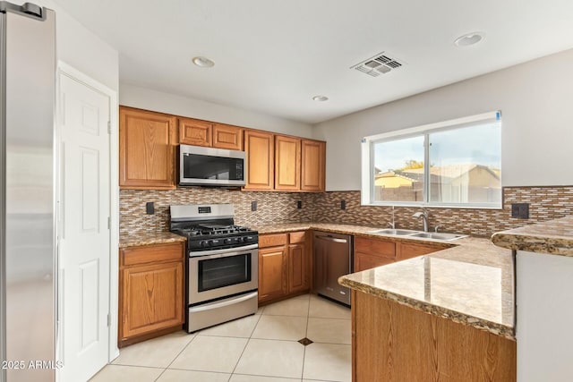 kitchen with sink, appliances with stainless steel finishes, light stone countertops, decorative backsplash, and a barn door