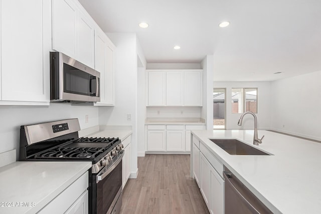 kitchen with white cabinetry, appliances with stainless steel finishes, light countertops, and a sink