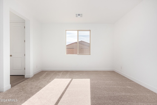 empty room with visible vents, light carpet, and baseboards