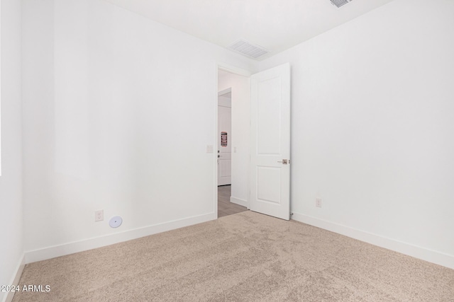 spare room with carpet floors, visible vents, and baseboards