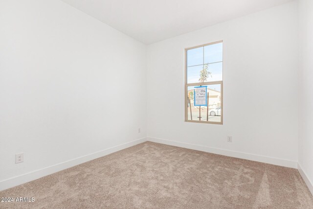 spare room with light carpet and baseboards