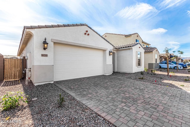 view of home's exterior featuring an attached garage, a tile roof, decorative driveway, and stucco siding