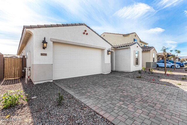 view of property exterior with decorative driveway, a tile roof, an attached garage, and stucco siding