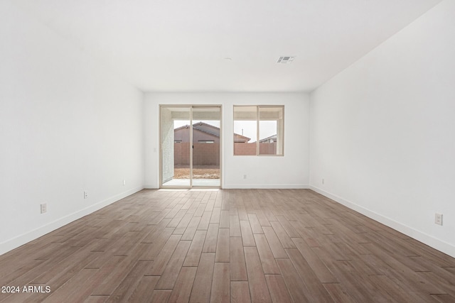 unfurnished room featuring visible vents, baseboards, and wood finished floors