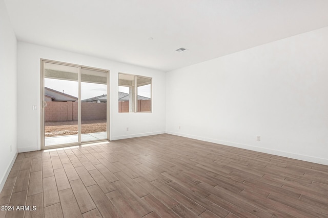 empty room with visible vents, baseboards, and wood finished floors