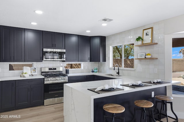 kitchen featuring a peninsula, a breakfast bar area, appliances with stainless steel finishes, and a sink