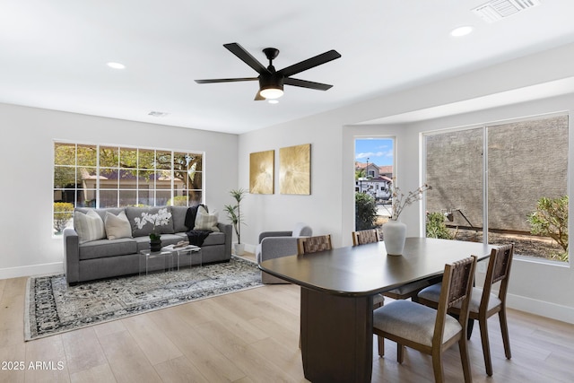 dining room featuring light wood finished floors, a ceiling fan, visible vents, and baseboards