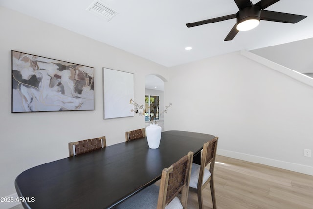 dining room featuring arched walkways, light wood finished floors, recessed lighting, visible vents, and baseboards