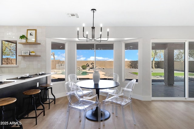 dining space featuring light wood-type flooring, plenty of natural light, visible vents, and an inviting chandelier