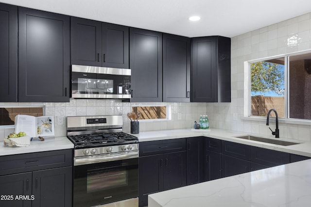 kitchen featuring light stone counters, stainless steel appliances, recessed lighting, decorative backsplash, and a sink