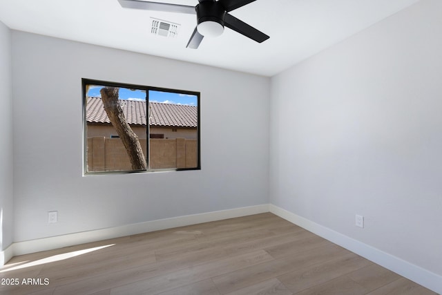 unfurnished room with a ceiling fan, visible vents, baseboards, and wood finished floors