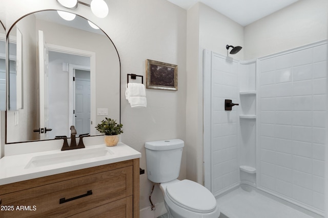 full bathroom featuring toilet, tiled shower, and vanity