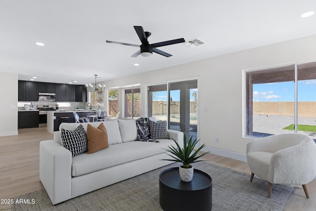 living room featuring light wood-type flooring, visible vents, baseboards, and recessed lighting