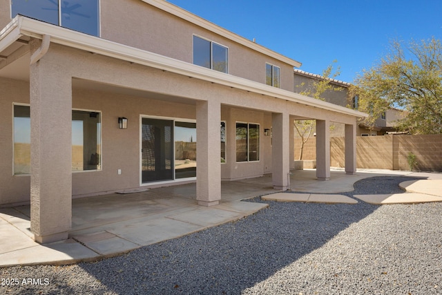 rear view of property with stucco siding, fence, and a patio