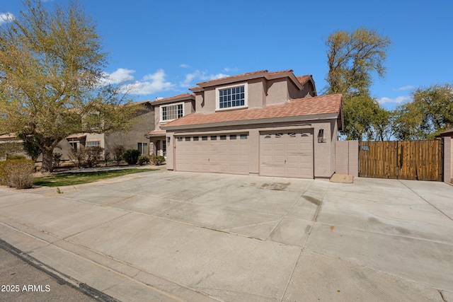 view of front of home with concrete driveway, an attached garage, a gate, and stucco siding