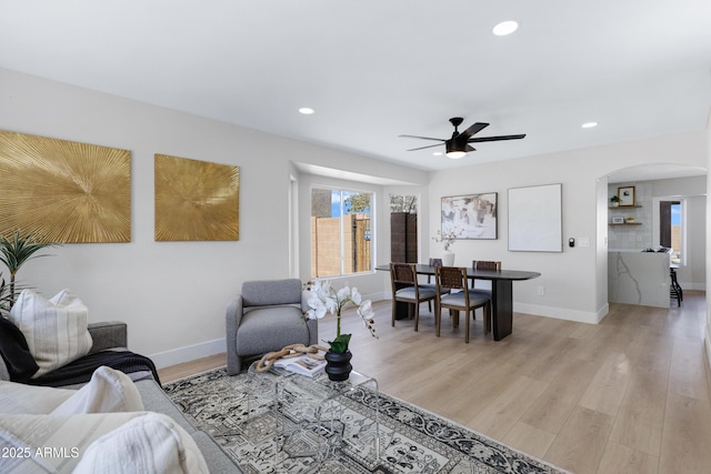 living room featuring arched walkways, a wealth of natural light, and light wood-style floors