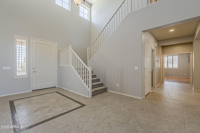 tiled foyer entrance featuring baseboards, recessed lighting, a towering ceiling, and stairway