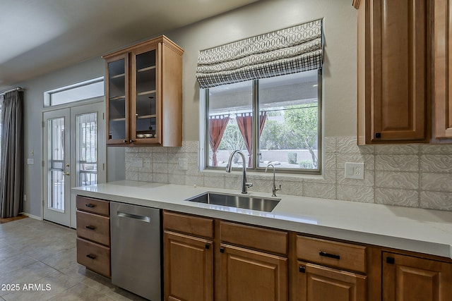kitchen featuring light countertops, a sink, dishwasher, glass insert cabinets, and brown cabinets