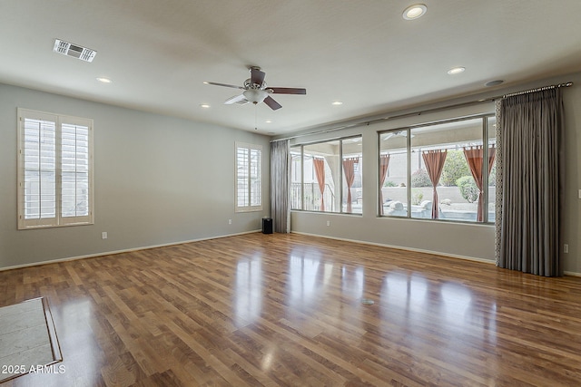 spare room featuring wood finished floors, a healthy amount of sunlight, and ceiling fan