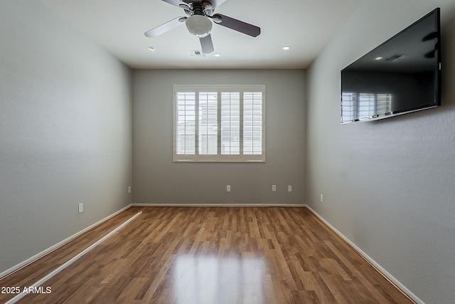 empty room with baseboards, ceiling fan, visible vents, and wood finished floors
