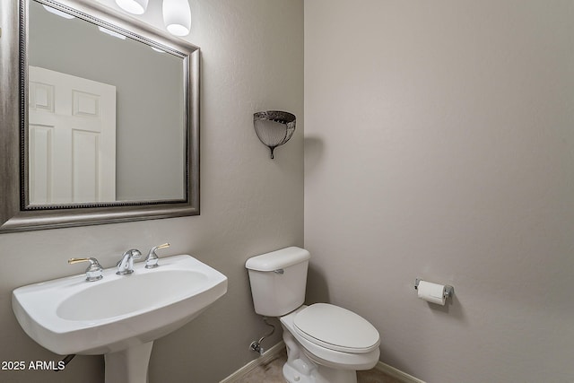 bathroom featuring toilet, a sink, and baseboards