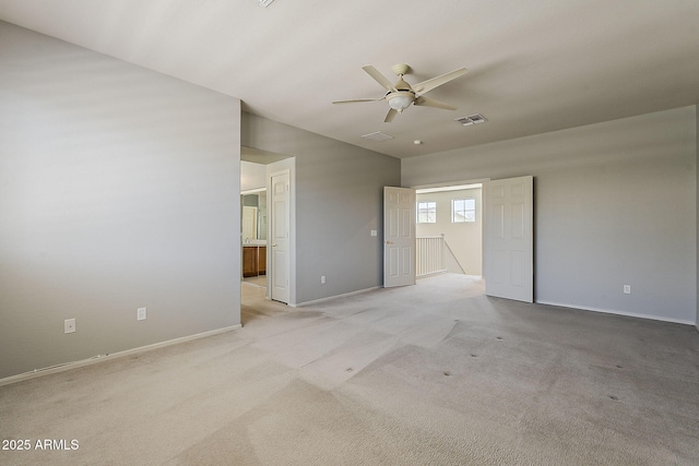 unfurnished bedroom featuring visible vents, baseboards, connected bathroom, vaulted ceiling, and light colored carpet