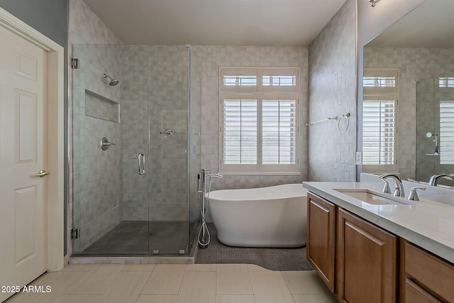 bathroom with vanity, a shower stall, a soaking tub, tile patterned flooring, and tile walls