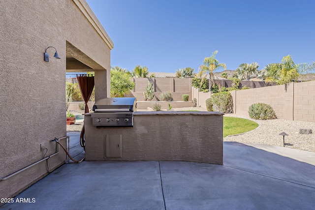 view of patio / terrace featuring a fenced backyard, exterior kitchen, and area for grilling