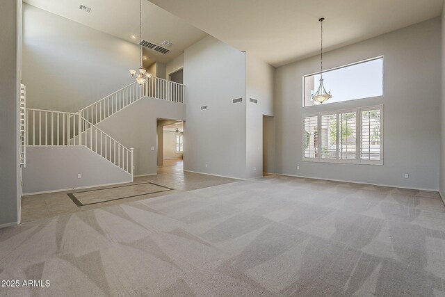 unfurnished living room with visible vents, carpet floors, stairway, and an inviting chandelier