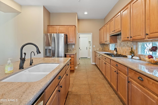 kitchen featuring sink, appliances with stainless steel finishes, tasteful backsplash, light stone countertops, and light tile patterned flooring