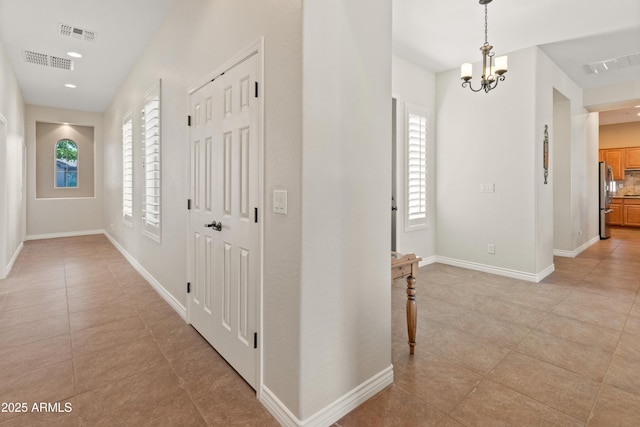 hall featuring light tile patterned floors and a notable chandelier