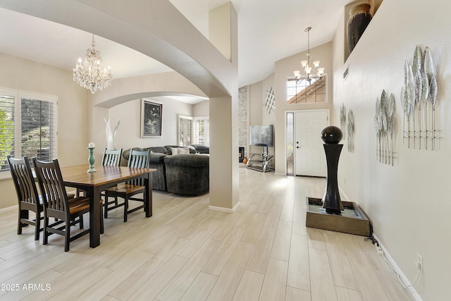 25042 S Hollygreen Dr, Sun Lakes, AZ 85248 - dining space with arched walkways, a high ceiling, light wood-type flooring, and a notable chandelier