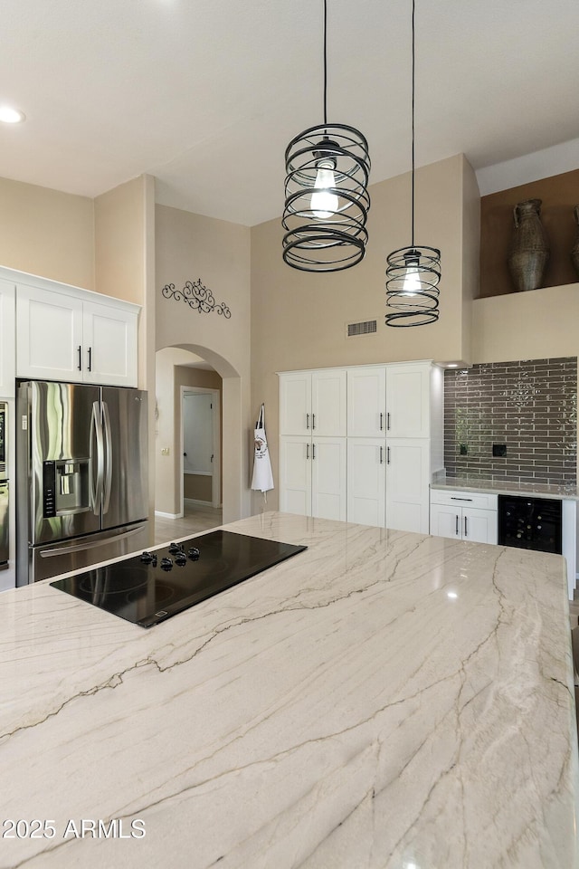 25042 S Hollygreen Dr, Sun Lakes, AZ 85248 - kitchen with visible vents, decorative backsplash, light stone countertops, arched walkways, and stainless steel appliances