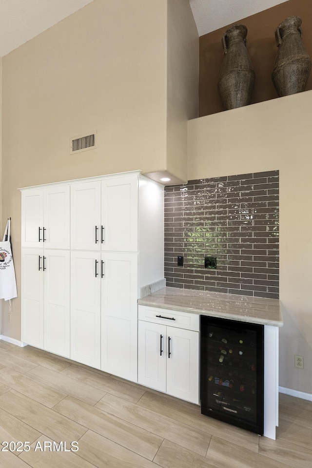 25042 S Hollygreen Dr, Sun Lakes, AZ 85248 - kitchen featuring beverage cooler, visible vents, light stone counters, and a towering ceiling