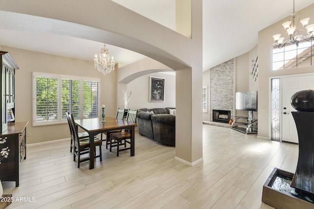 25042 S Hollygreen Dr, Sun Lakes, AZ 85248 - dining room with a fireplace, high vaulted ceiling, baseboards, a notable chandelier, and light wood-style flooring