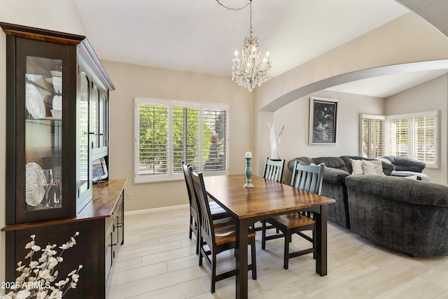 25042 S Hollygreen Dr, Sun Lakes, AZ 85248 - dining area featuring light wood-style floors, arched walkways, vaulted ceiling, baseboards, and an inviting chandelier