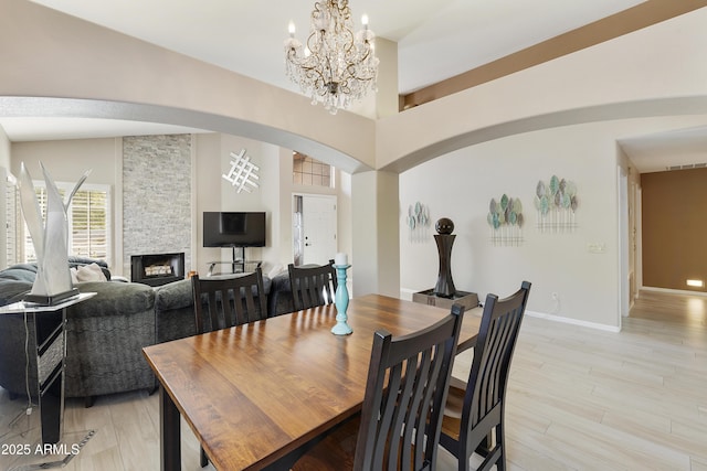 25042 S Hollygreen Dr, Sun Lakes, AZ 85248 - dining space featuring a high ceiling, a fireplace, arched walkways, a chandelier, and visible vents