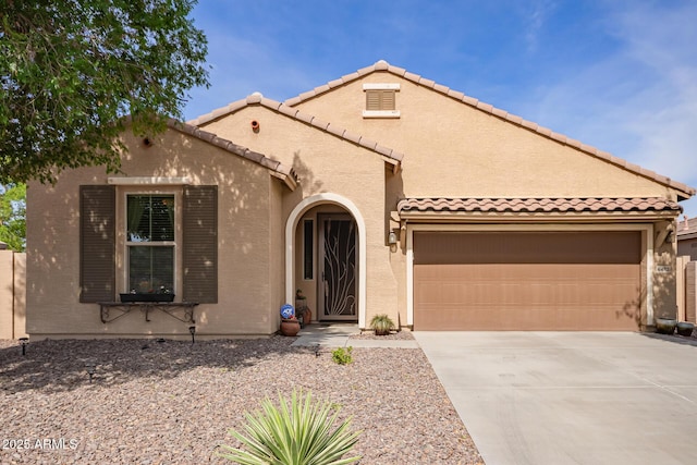 mediterranean / spanish-style home with a tiled roof, concrete driveway, a garage, and stucco siding