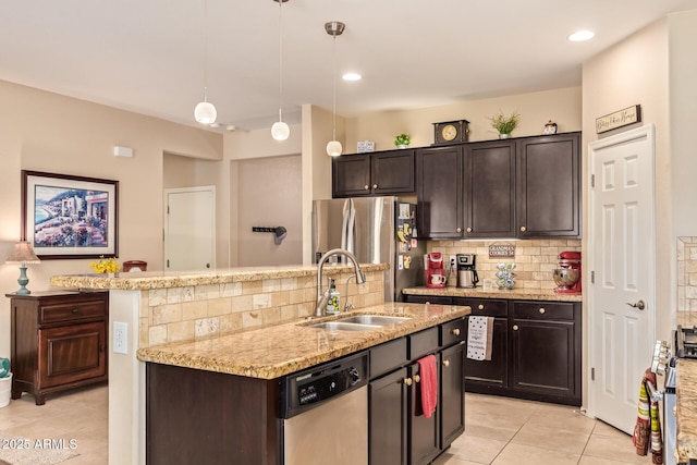 kitchen with stainless steel appliances, a sink, light tile patterned floors, decorative backsplash, and a center island with sink