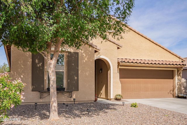 view of front of property featuring stucco siding, driveway, a garage, and a tiled roof