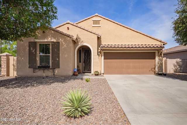 mediterranean / spanish-style house with an attached garage, concrete driveway, a tiled roof, fence, and stucco siding