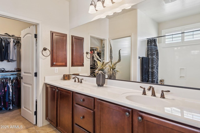 full bath with double vanity, a sink, and a walk in closet