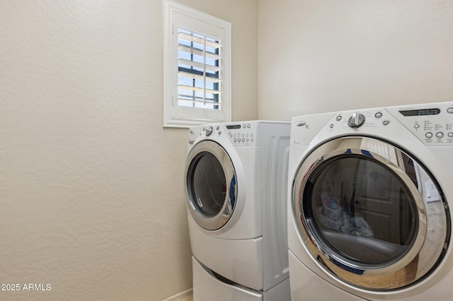 laundry room featuring a textured wall, laundry area, and washing machine and clothes dryer