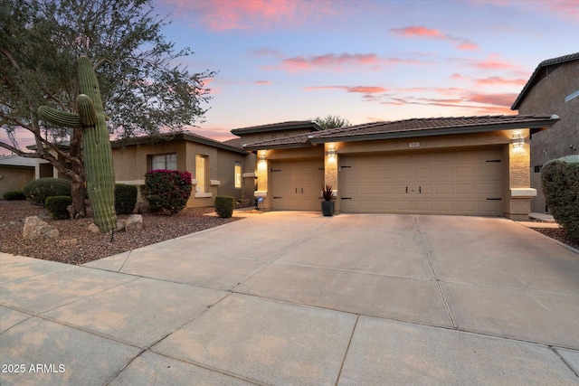 view of front facade featuring a garage, driveway, a tile roof, and stucco siding